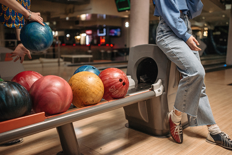 A woman sits on a bowling ball dispenser