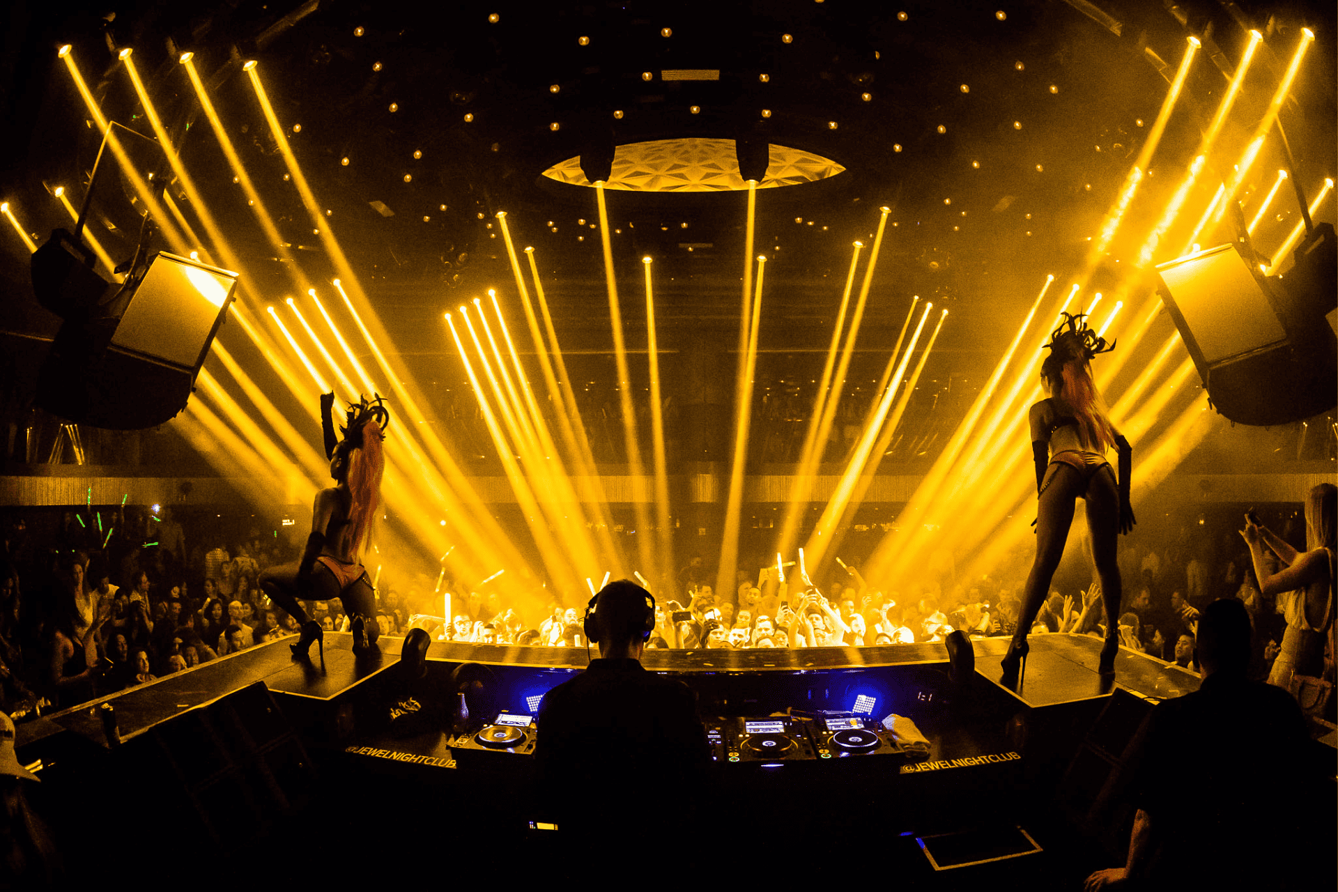A DJ and two dancers on stage at a Las Vegas nightclub during Exodus Festival