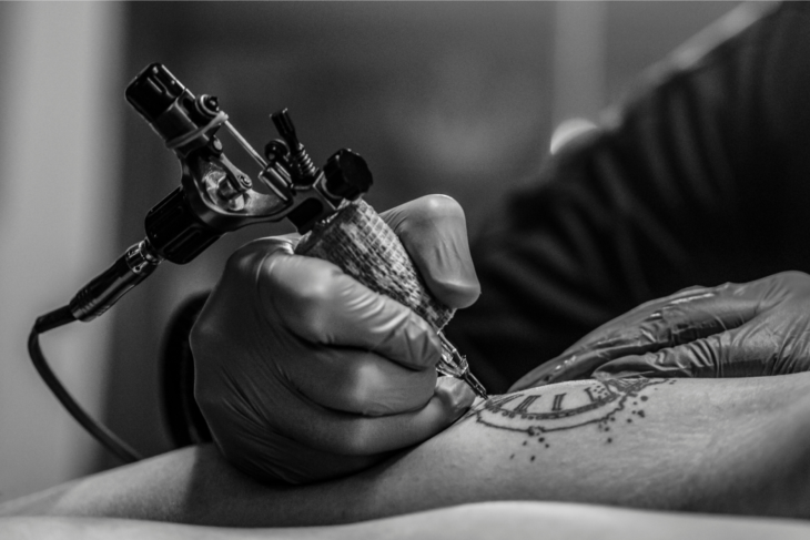 a black and white image of a tattoo artist giving someone a tattoo