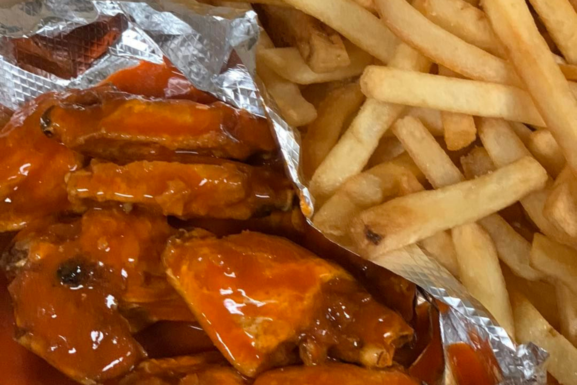 Fried hot wings and fries from Boston Pizza Las Vegas in aluminum foil
