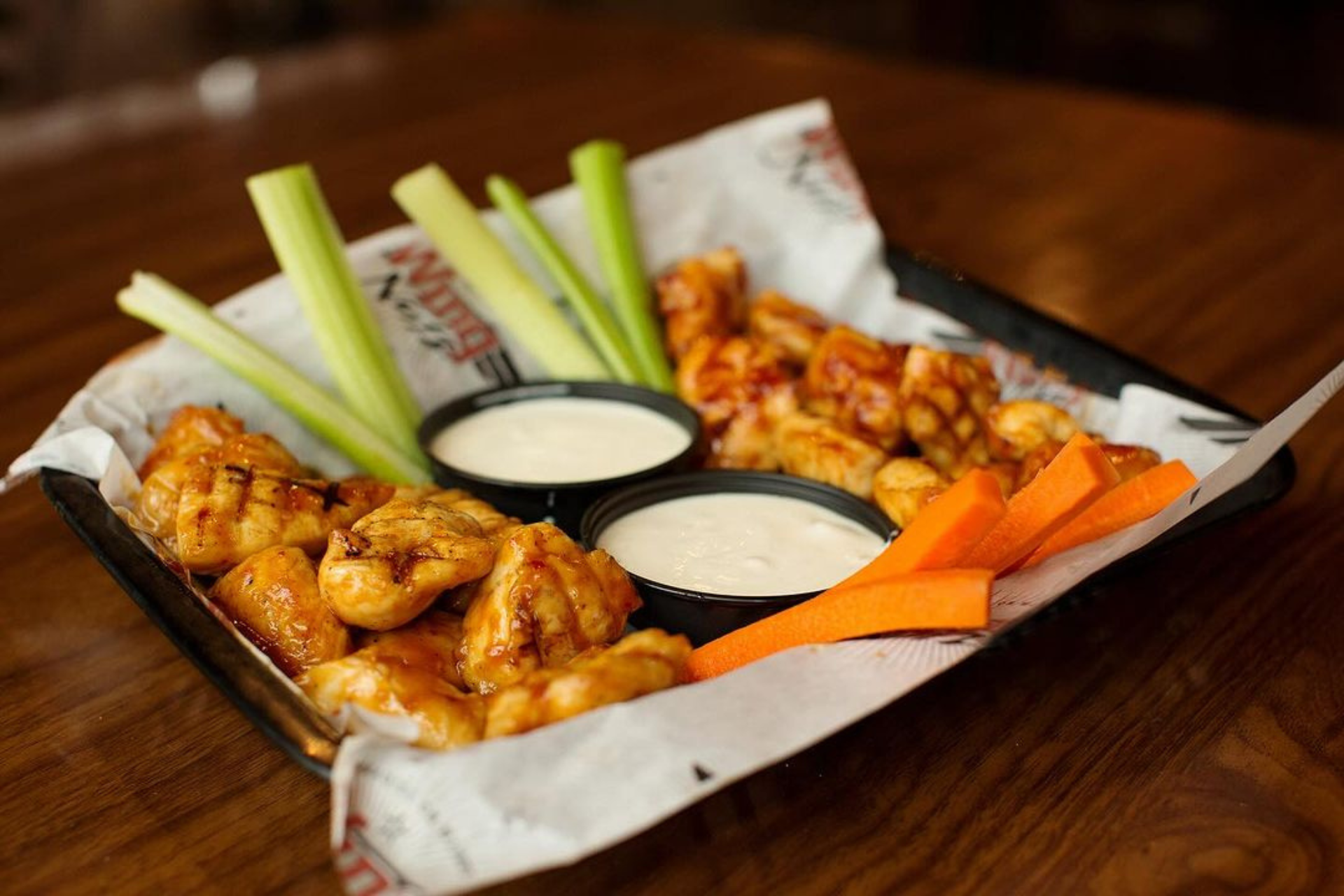 A tray of boneless wings from Wing Nutz Las Vegas with sauce, carrots, and celery