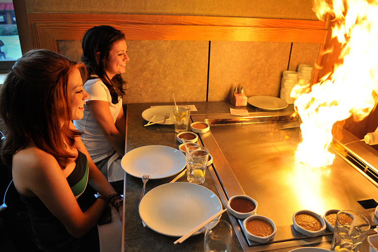 Two women enjoying a hibachi-style dinner show