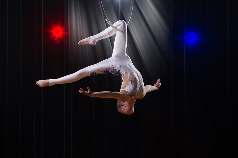 A circus performer suspended from a hanging ring
