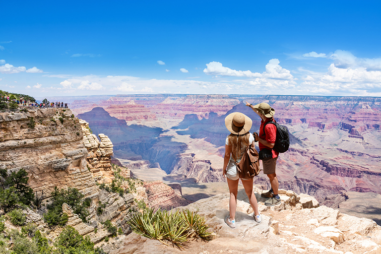 A couple on top of a mountain enjoying a view of the Grand Canyon